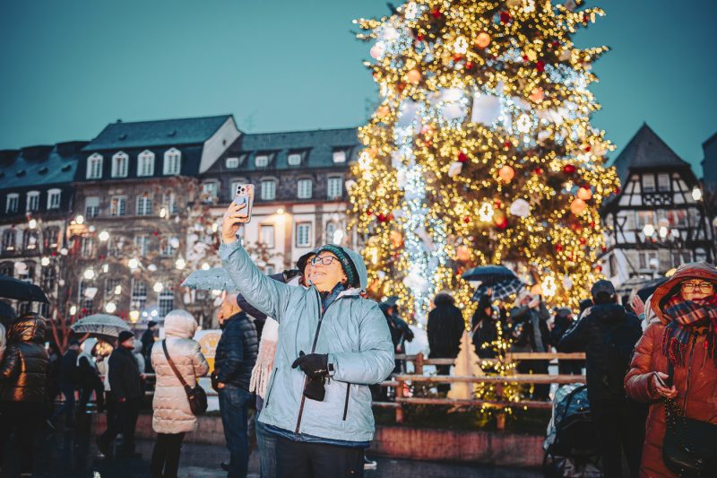Marché de Noel 2024 avec sapin et gens sous parapluies place Kléber