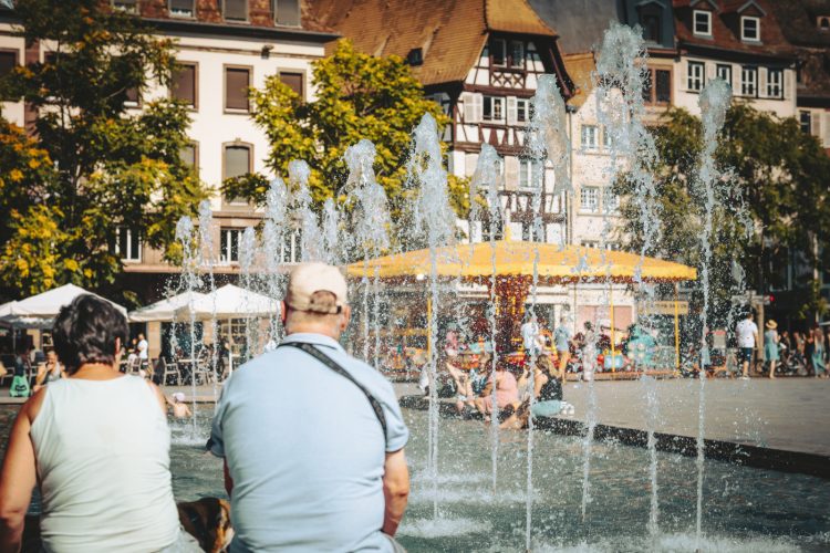 Couple devant fontaine et manège, place Kléber en été