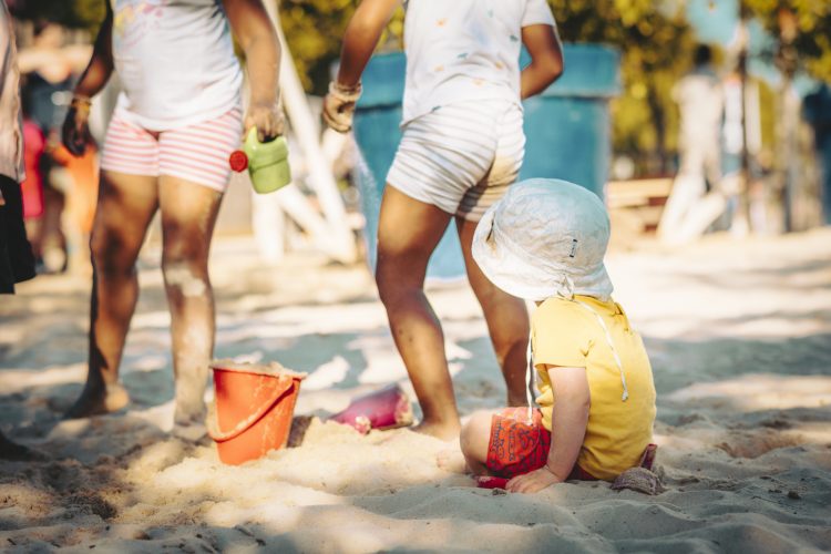 Enfant de dos jouants sur la plage aux château de sable