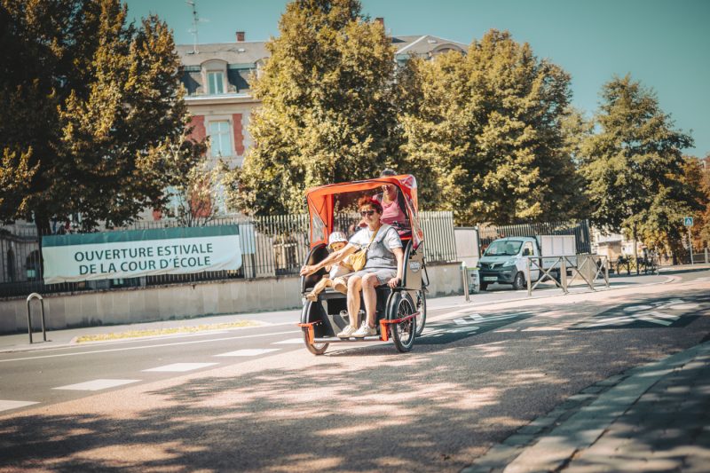 Famille sur triporteur devant école estivale